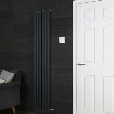 Milano Connect white backlit wifi thermostat for electric heating by black Aruba radiator on black wall nearby white door and black chair with cushions