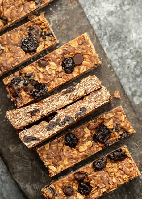 overhead image of dark chocolate cherry granola bars lined across a stone cutting board