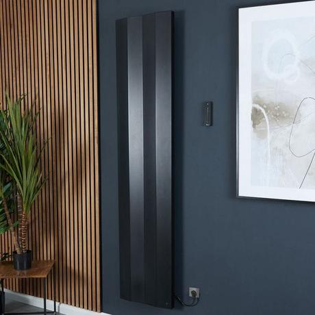 Milano Notus V black aluminum vertical electric plug-in designer radiator on dark blue wall nearby wooden panelling and large framed artwork