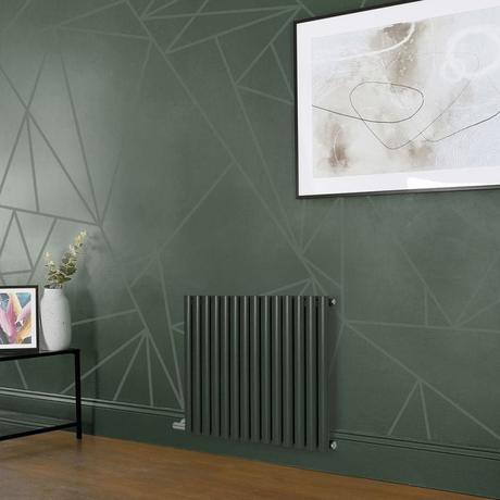Milano Aruba electric evergreen horizontal designer radiator on green wall beneath large framed artwork nearby small table with vase and framed picture