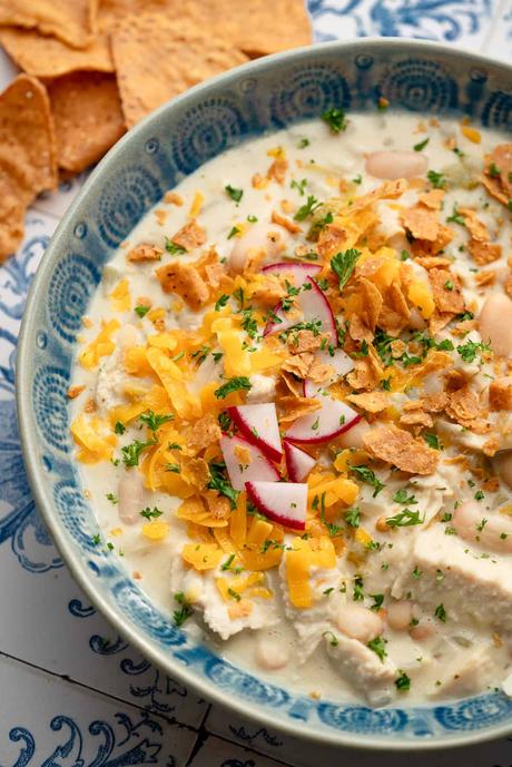 close up image of white bean chili in blue bowl on decorative background