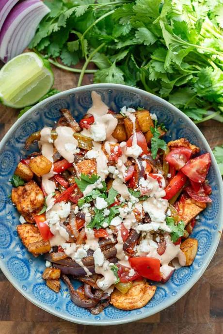an overhead shot of a fiesta potato bowl with chipotle crema with cilantro and lime on the side