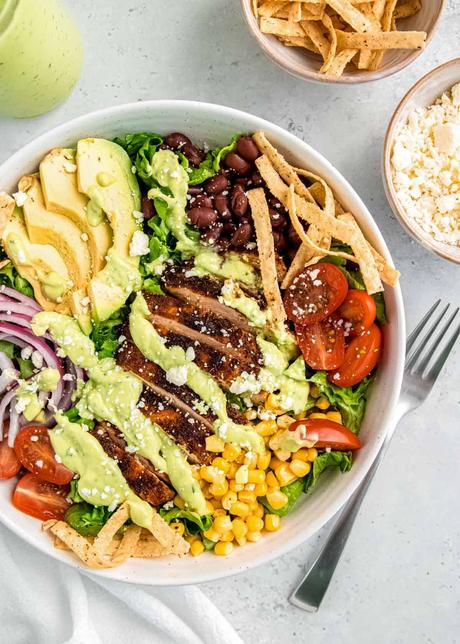 southwest chicken salad in a white bowl on a white table with a fork and cotija cheese