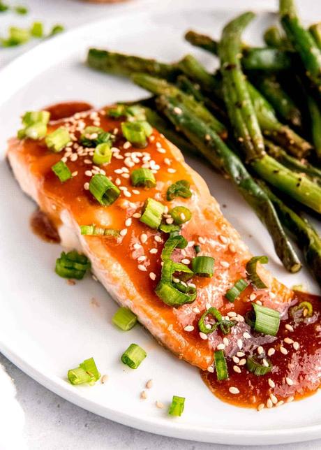 overhead image of a baked salmon filet and green beans on a white plate