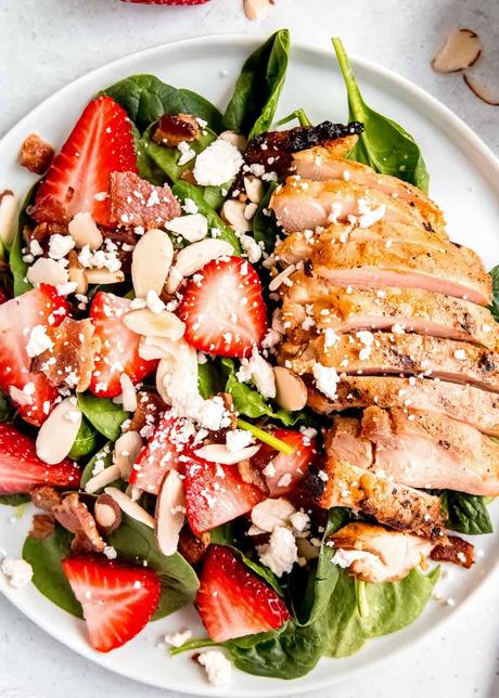 overhead image of strawberry spinach salad on a white plate