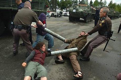 image above: Stryker vehicles roll into the Port of Olympia 5/23/06. Photo by Tony Overman Sheriff's deputies pull a trio of linked protesters to the side of the road to clear entry into the port.