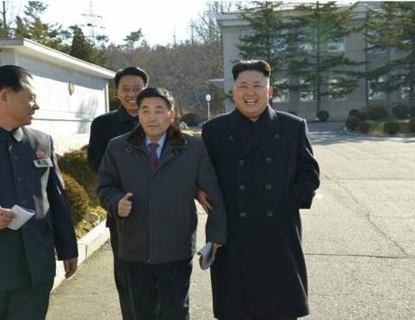 Kim Jong Un links arms with a manger at the Pyongyang Weak Current Apparatus Factory (Photo: Rodong Sinmun).