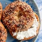 an overhead shot of a toasted everything bagel on a blue plate