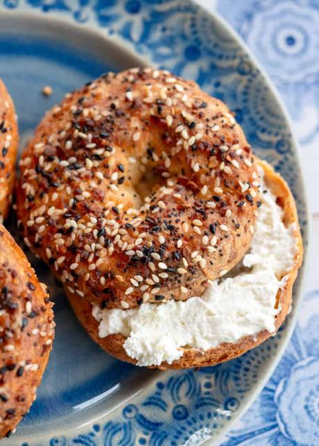 an overhead shot of a toasted everything bagel on a blue plate