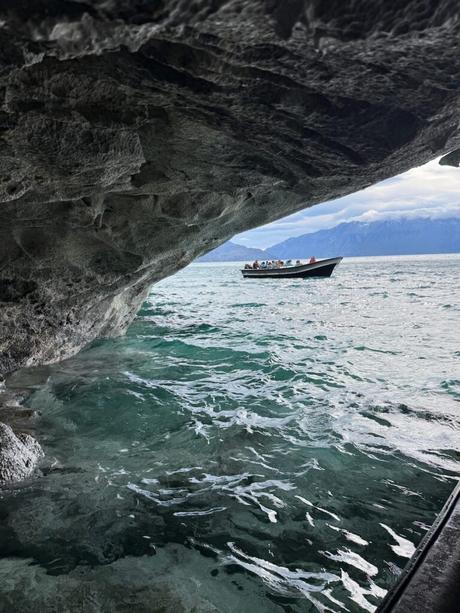 Boat carrying visitors past an overhanging marble cavern on Lago General Carrera near Puerto Río Tranquilo, Chile