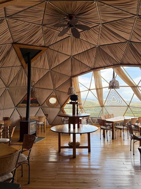 Dining area inside a geodesic dome at EcoCamp Patagonia, with wooden tables, a stove and mountain views