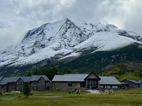 Wooden buildings of the Las Torres Hotel beneath snow-covered mountains in Torres del Paine National Park
