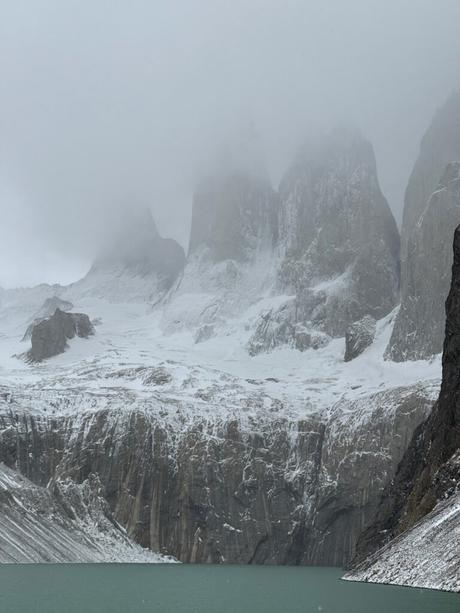 Snow-covered granite towers rising through low cloud above the lagoon at Mirador Base Torres