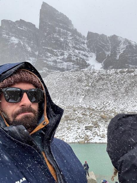 Alex Tiffany and other hikers sheltering in waterproof jackets during snowfall at Mirador Base Torres in Chilean Patagonia