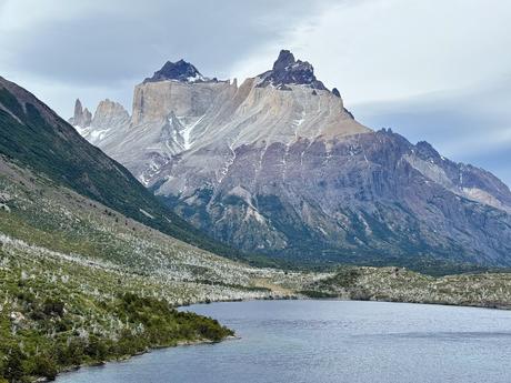 Cuernos del Paine rising above a lake and fire-damaged woodland along the Torres del Paine W Trek