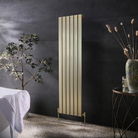 Milano Alpha brushed brass flat panel vertical single panel designer radiator on black wall nearby table with vase and candle