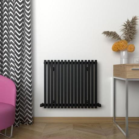Carisa Sophia black aluminum horizontal designer radiator on white wall nearby black and white curtain and small desk with vase