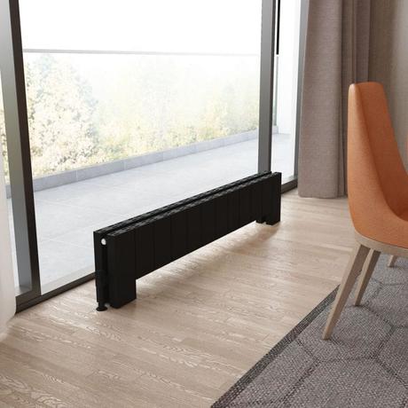 Carisa Elvino black floor horizontal aluminum designer radiator on light wooden flooring in front of large window