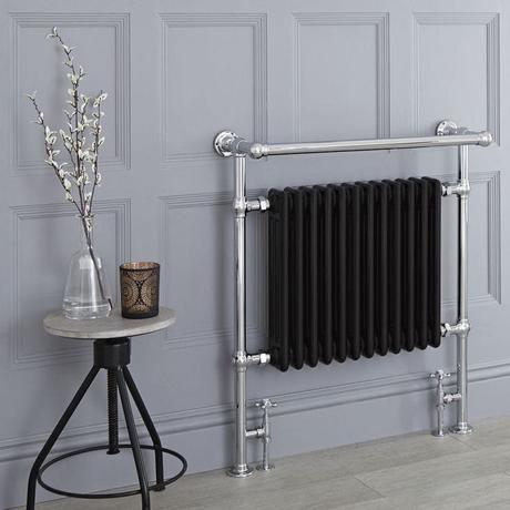 Milano Elizabeth black traditional heated towel rail on light gray wall nearby small table with clear vase