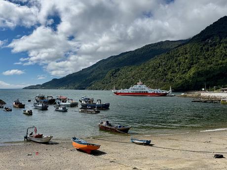 Fishing boats in Caleta La Arena harbour with a vehicle ferry at the Reloncaví Estuary terminal