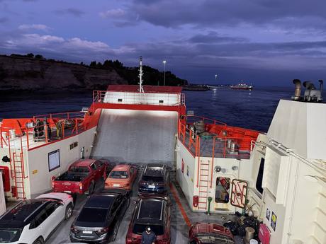 Cars and pickup trucks packed onto a vehicle ferry in southern Chile, with the loading ramp raised at dusk.