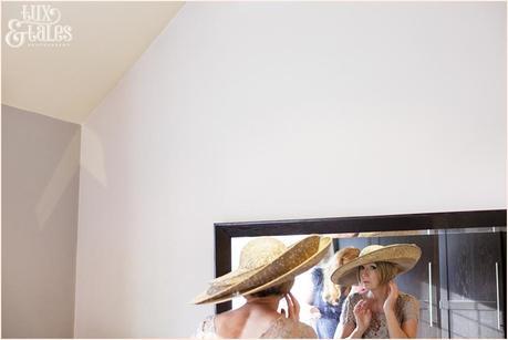 Bride adjusts hat in mirror at hogarths hotel wedding