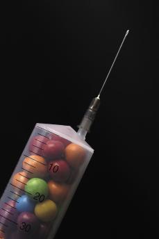 Close up of a syringe filled with candy in isolated
