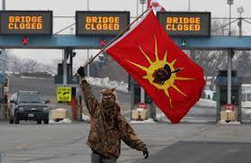 A man waves a flags as Aboriginal protesters and supporters in the Idle No More movement block the Blue Water Bridge border crossing to the United States in Sarnia, Ont. on Saturday. The closing of the bridge lasted about an hour. Jan 5, 2013