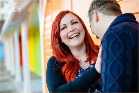 A cute couple laughs at each other ine Scarborough at engagement shoot