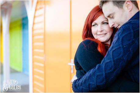 Couple cuddles inf ront fo beach huts in scarborough at North BEach