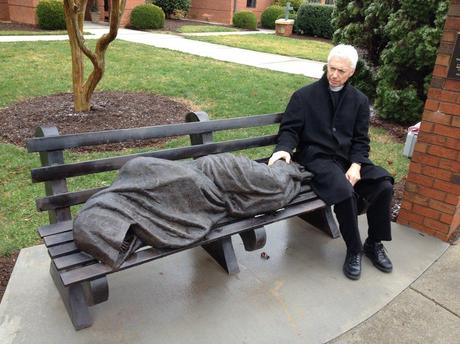 The Rev. David Buck sits next to the Jesus the Homeless statue that was installed in front of his church, St. Alban's Episcopal, in Davidson, N.C.