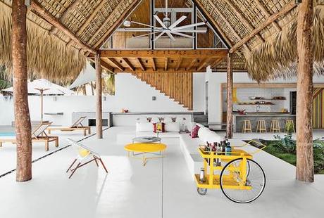 the white floor and thatched roof of the living dining space of a house in El Salvador