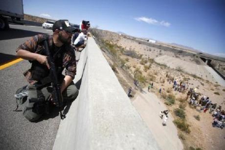 An armed man stands watch as protesters gather by the Bureau of Land Management's base camp near Bunkerville, Nevada