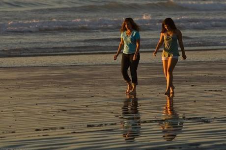 A Mother Daughter team (presumably) walk barefoot together on the beach