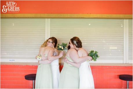 Two brides hug their bridesmaids