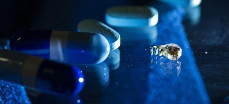 A batteryless electrostimulator next to medicinal pills for size comparison. The new powering method allows the device to be wirelessly powered deep inside the body.