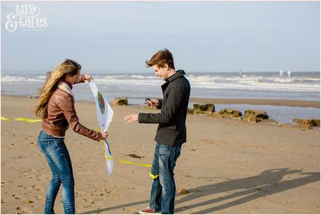 Engaged couple fly a kite at fristhorpe beach
