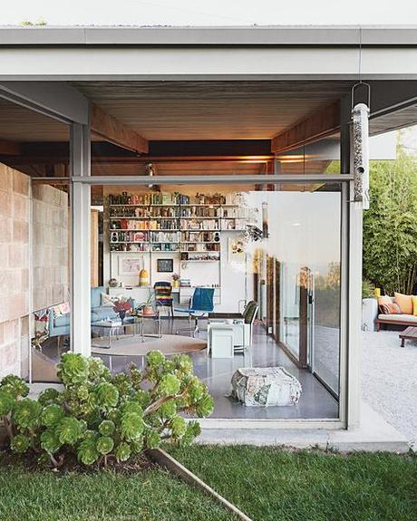 Modern glass walled living room in a renovated A Quincy Jones Home in the Mutual Housing Association neighborhood in Los Angeles with blue sofa and sisal rug.
