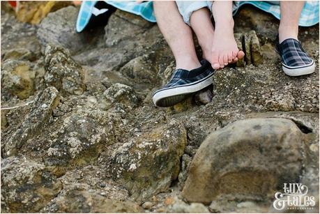 couple cuddling on the rocks in Scarborough engagement shoot