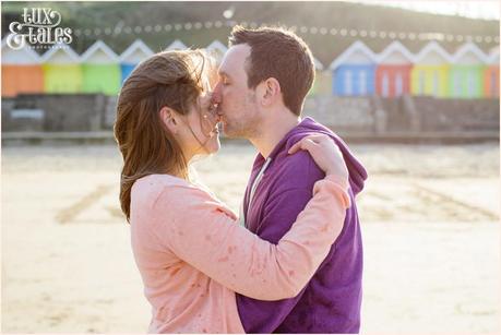 Couple kidding in front of the rainbow beach huts in Scarborough engagement photography