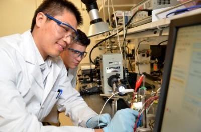 Postdoctoral scholar Shu Hu (foreground) demonstrates how to make photoelectrochemical measurements of a solar-fuels cell