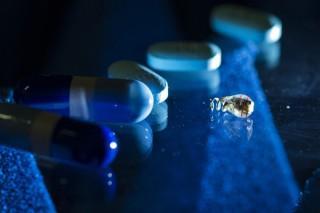 A batteryless electrostimulator next to medicinal pills for size comparison. The new powering method allows the device to be wirelessly powered deep inside the body.