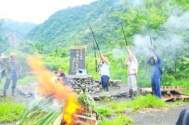 Residents of Mukumuqi Village in Hualien County’s Sioulin Township send up smoke signals and fire hunting rifles yesterday next to a memorial for victims of Typhoon Ofelia in 1990. Photo: Hua Meng-ching, Taipei Times