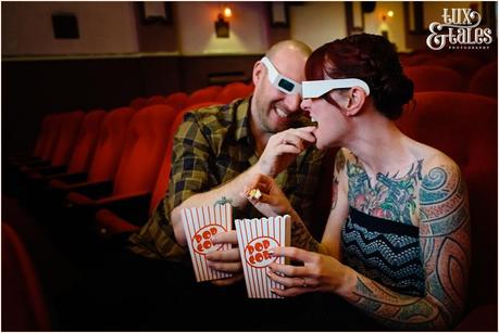 groom feeds bride popcorn at engagement shoot at Hyde Park Picture House
