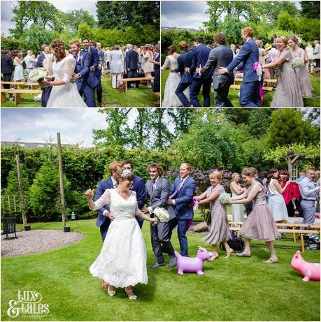 Bride and groom conga line up the aisle at Althrincham back garden wedding Tux & Tales Photography