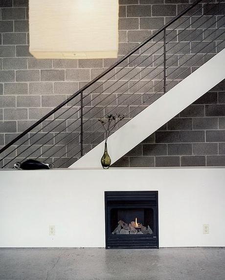 Still life with IKEA lampshade and ventless fireplace. The unfinished, black, welded- steel railing borders steps made of framing lumber, which emit a friendly, old-fashioned creak as Walz treads up and down.