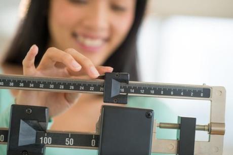 Midsection Of Woman Smiling While Adjusting Weight Scale