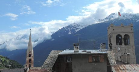 Torre campanario y tejados de Bormio junto a las cimas alpinas.